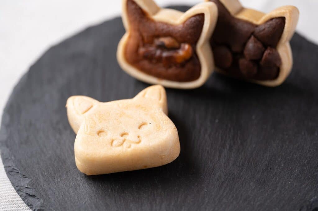 小麦不使用でつくられた猫の形のフィナンシェパイが黒いお皿に乗せられている。