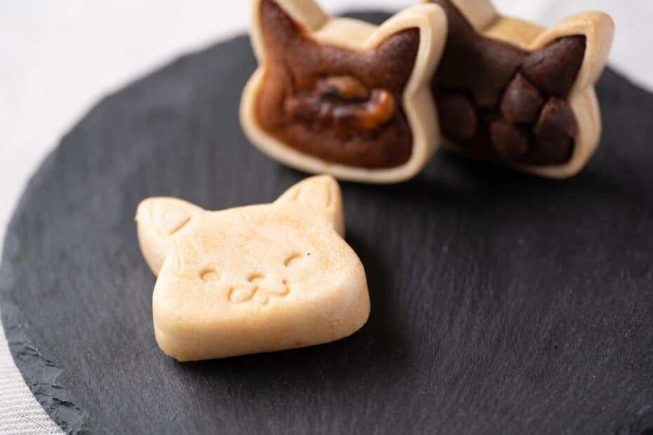 小麦不使用でつくられた猫の形のフィナンシェパイが黒いお皿に乗せられている。