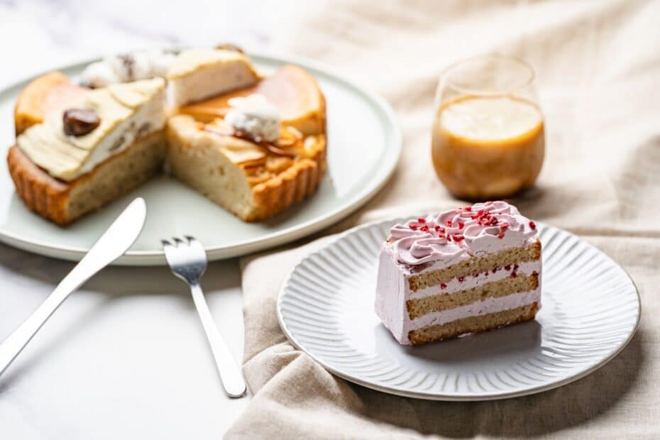 いろいろな種類のヴィーガン対応ケーキが並べられ、そのうちの1つであるピンクのバターケーキを食べようとしている。