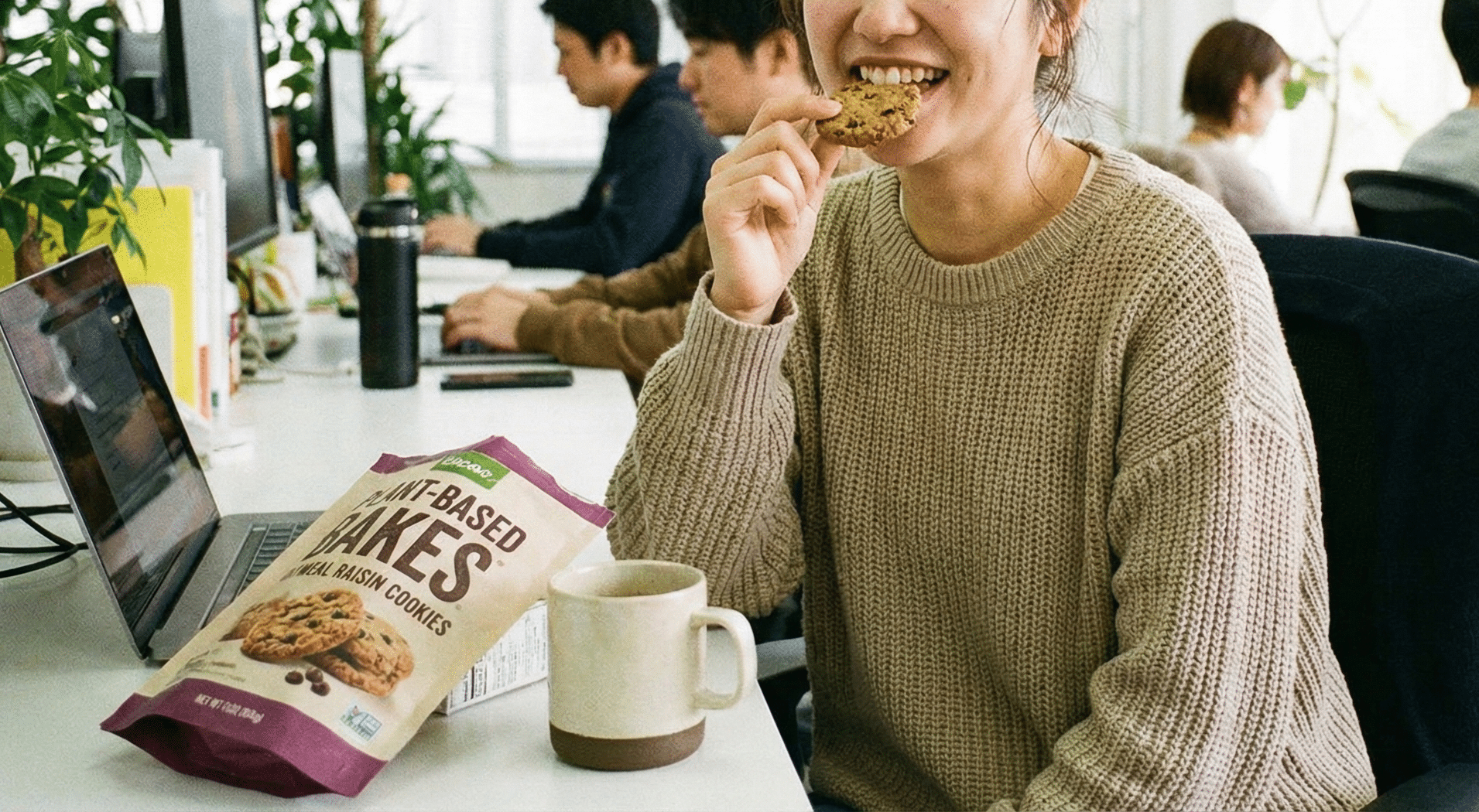 オフィスでヴィーガン対応のクッキーを間食に食べている女性。